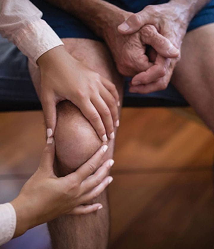 A person holding their knee with two hands