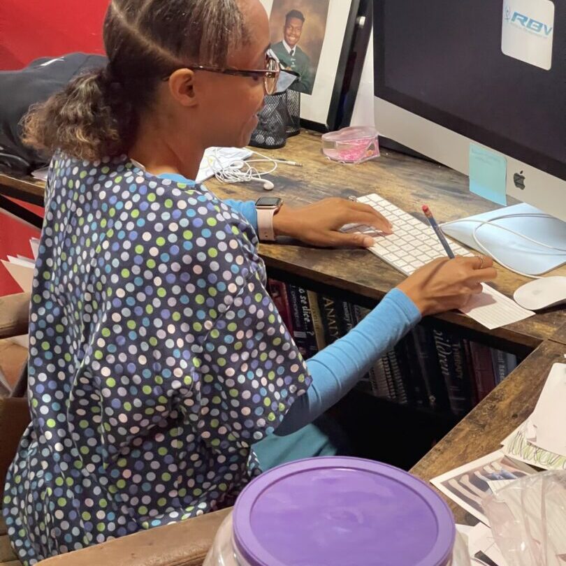 A woman sitting at a desk with papers and a computer.